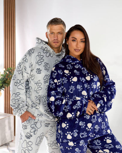 Two people wearing matching pajama sets with paw prints on a white background