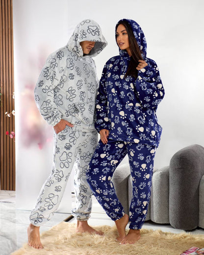 Two people wearing floral-patterned onesies in a living room setting.