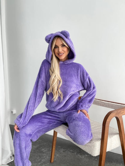 Person wearing a purple onesie with bear ears sitting on a chair.
