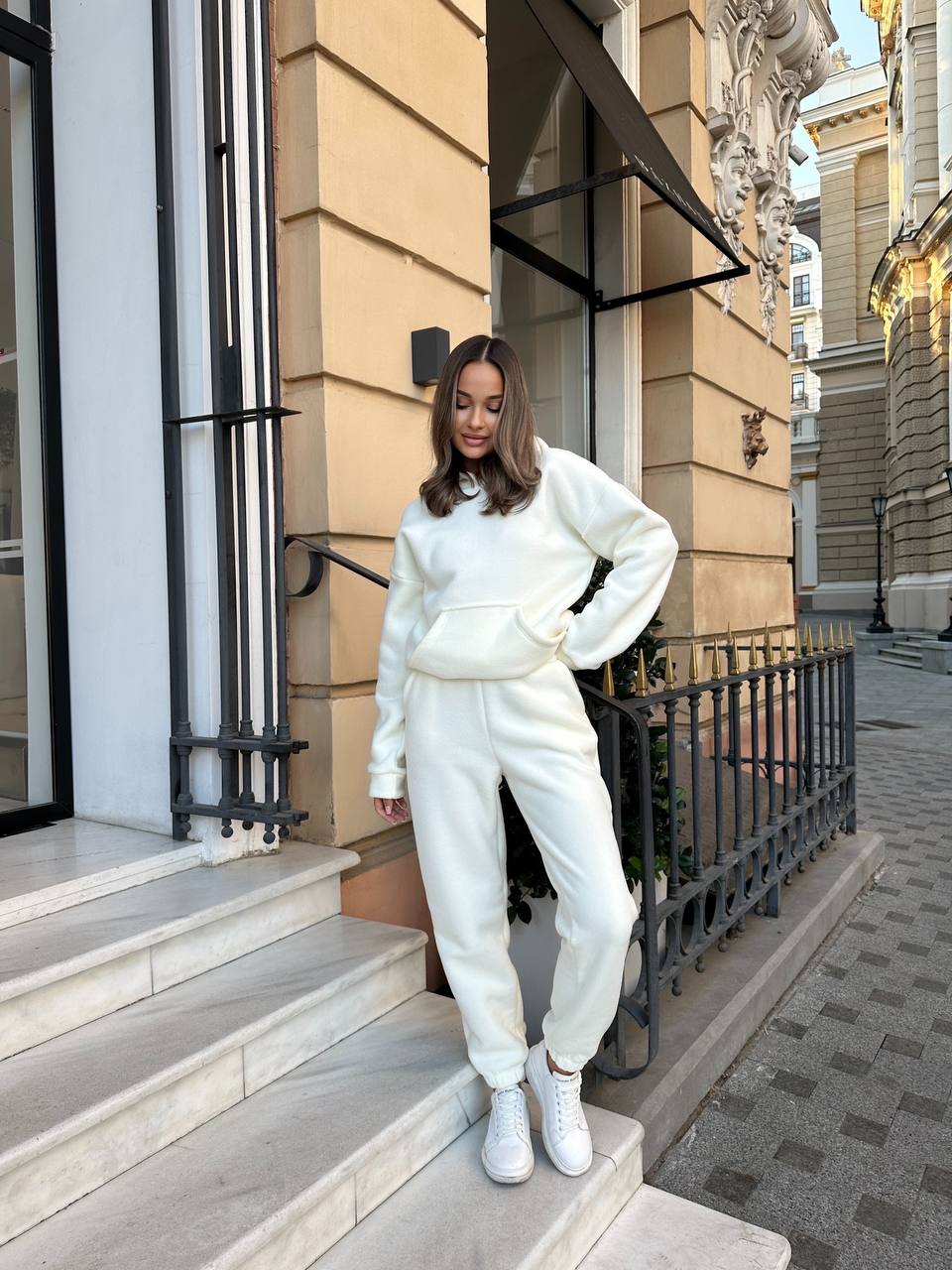 Woman in a white outfit standing on steps outside a building