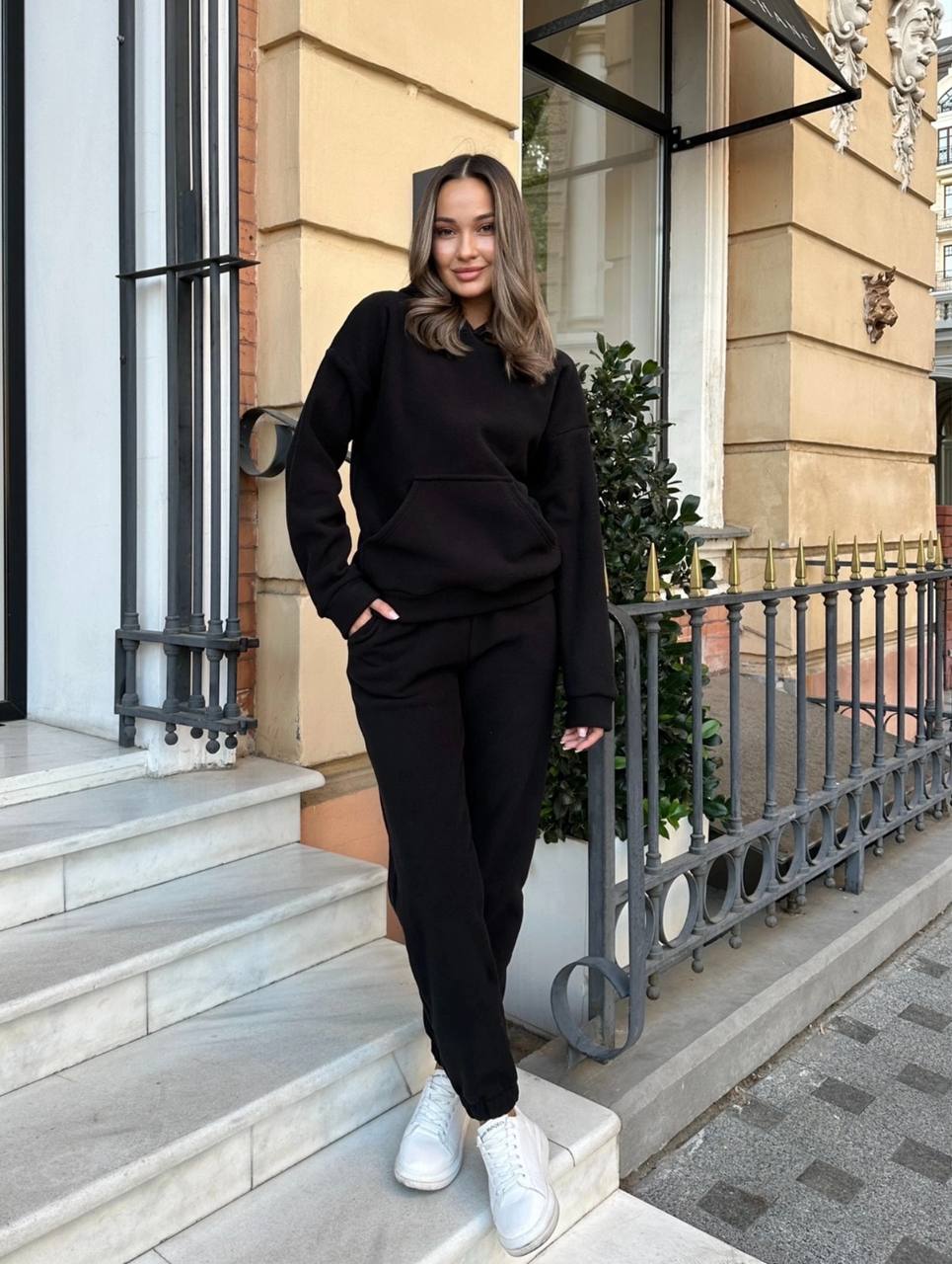 Woman in black outfit standing on steps outside a building