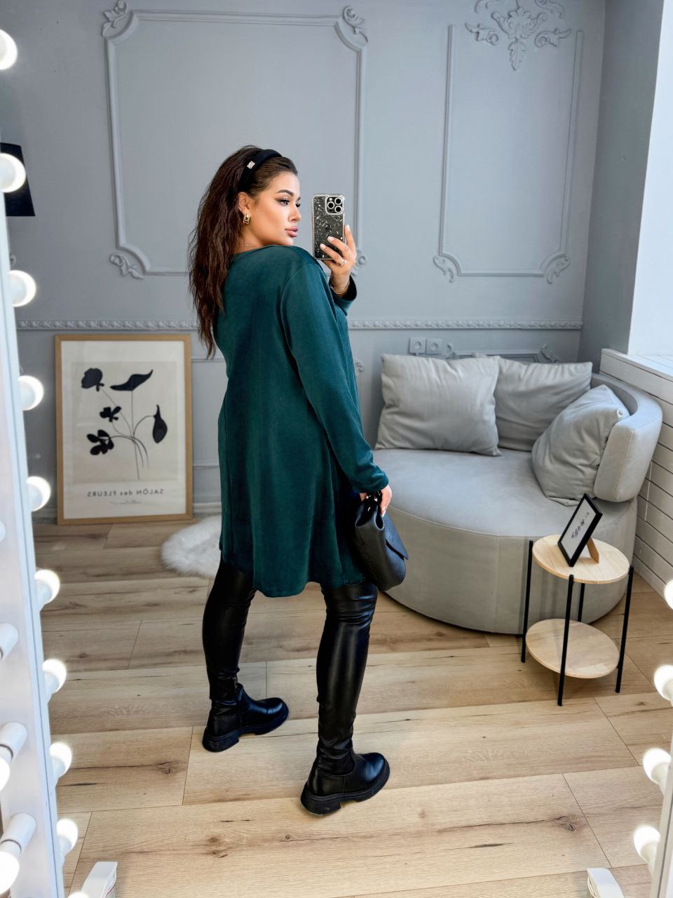 Woman taking a mirror selfie in a stylish room with a sofa and decor.