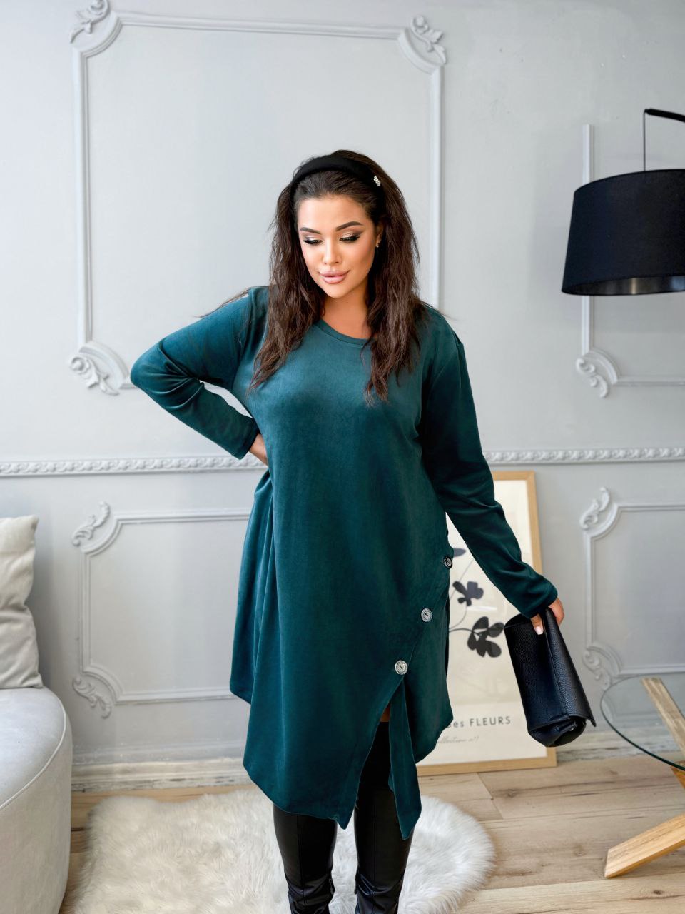 Woman in a teal dress standing in a room with decorative elements.