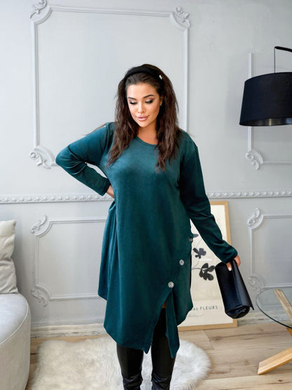 Woman in a teal dress standing in a room with decorative elements.