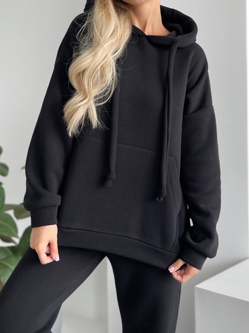 Person wearing a black hoodie with a neutral background