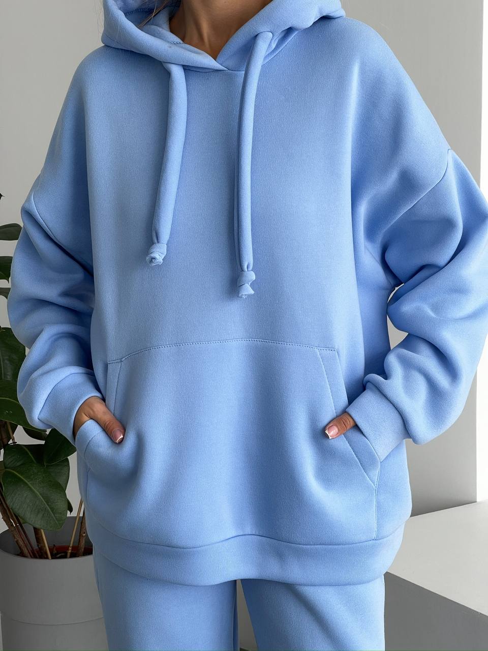 Person wearing a light blue hoodie with a neutral background