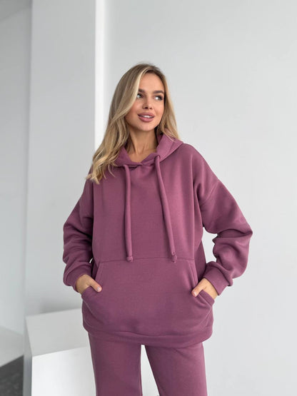 Woman wearing a purple hoodie and pants in a minimalistic setting