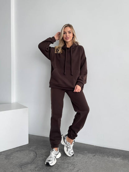 Woman wearing a brown tracksuit against a white background
