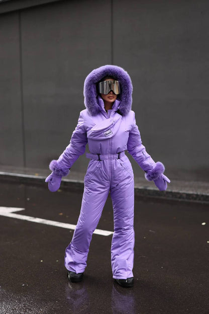 Person wearing a purple snowsuit with goggles on a dark surface.