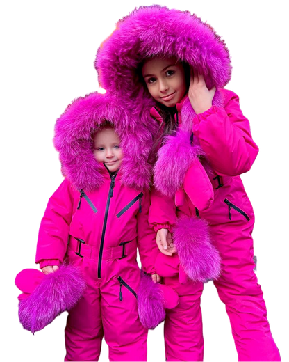 Two children wearing bright pink snowsuits with fur hoods on a white background