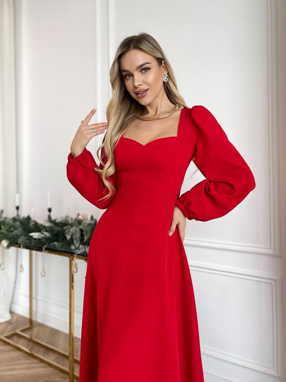 Woman wearing a red dress with long sleeves in an indoor setting.