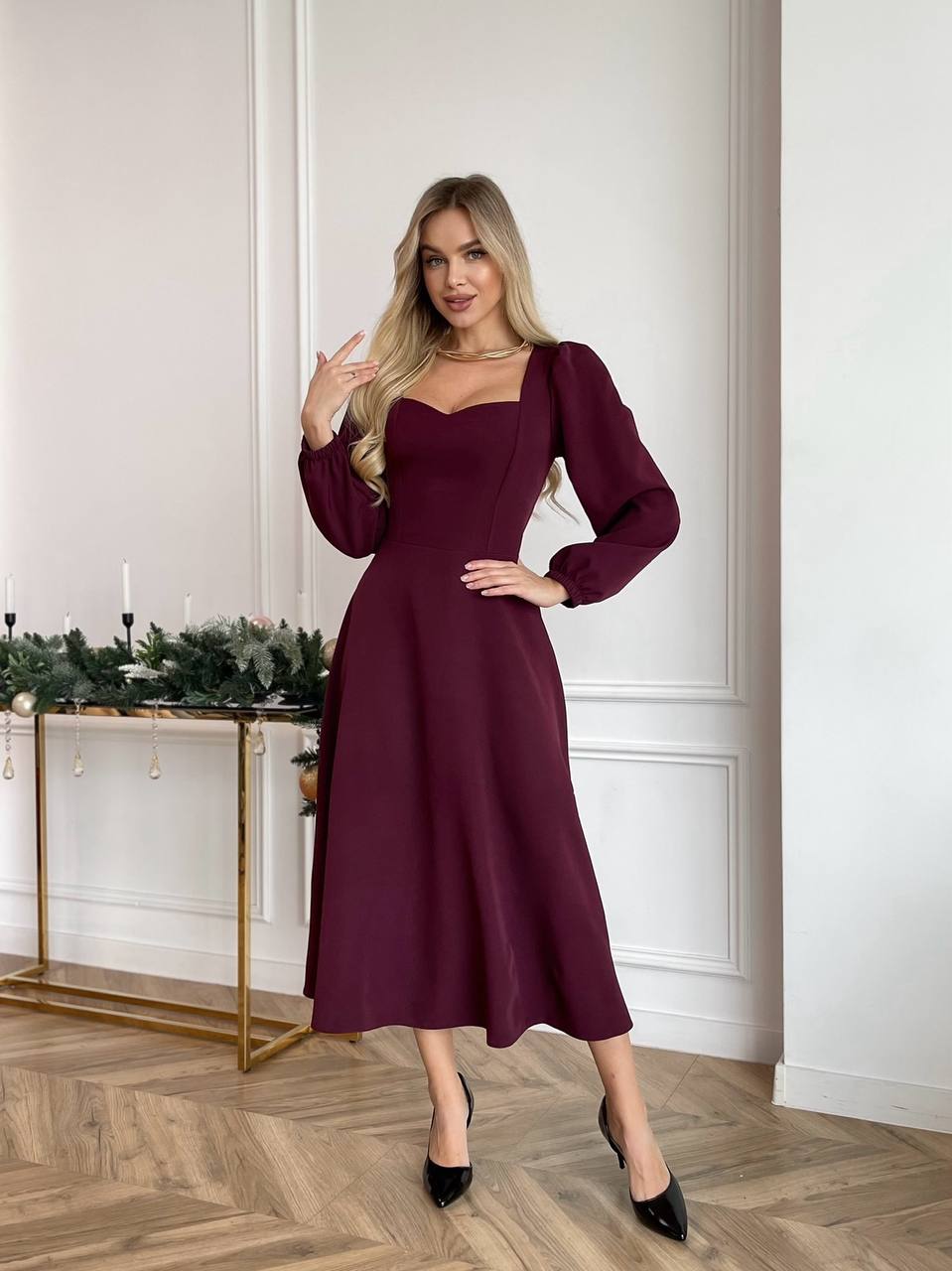 Woman wearing a burgundy dress in an elegant room with decorative elements.