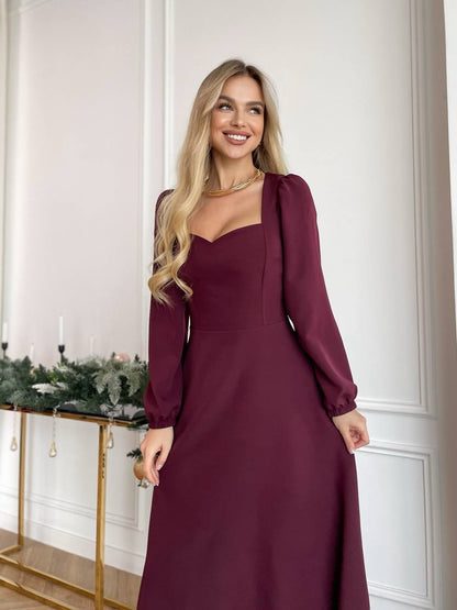 Woman wearing a burgundy dress standing in a room with decorative elements.