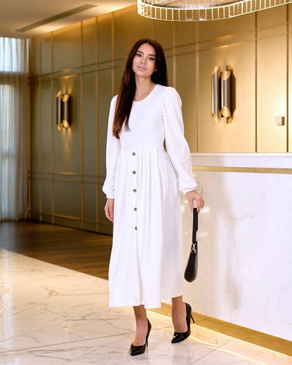 Woman in a white dress standing in an elegant interior setting