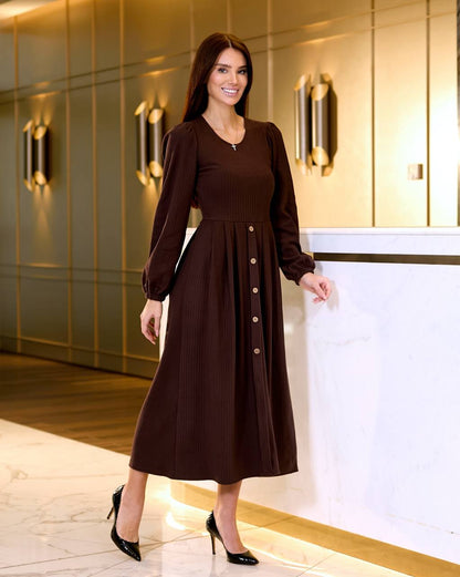 Woman in a brown dress standing in an elegant interior setting