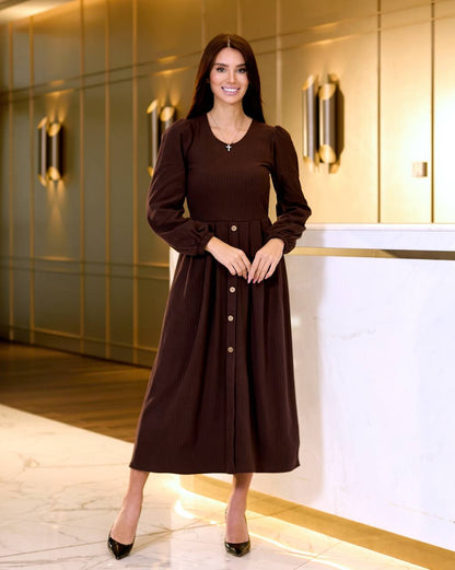 Woman in a brown dress standing in an elegant interior setting