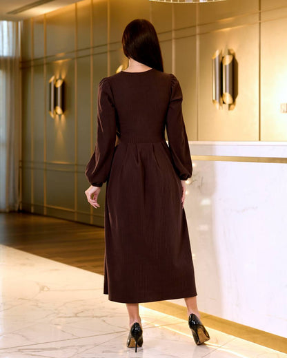 Woman in a brown dress standing in a stylish interior setting