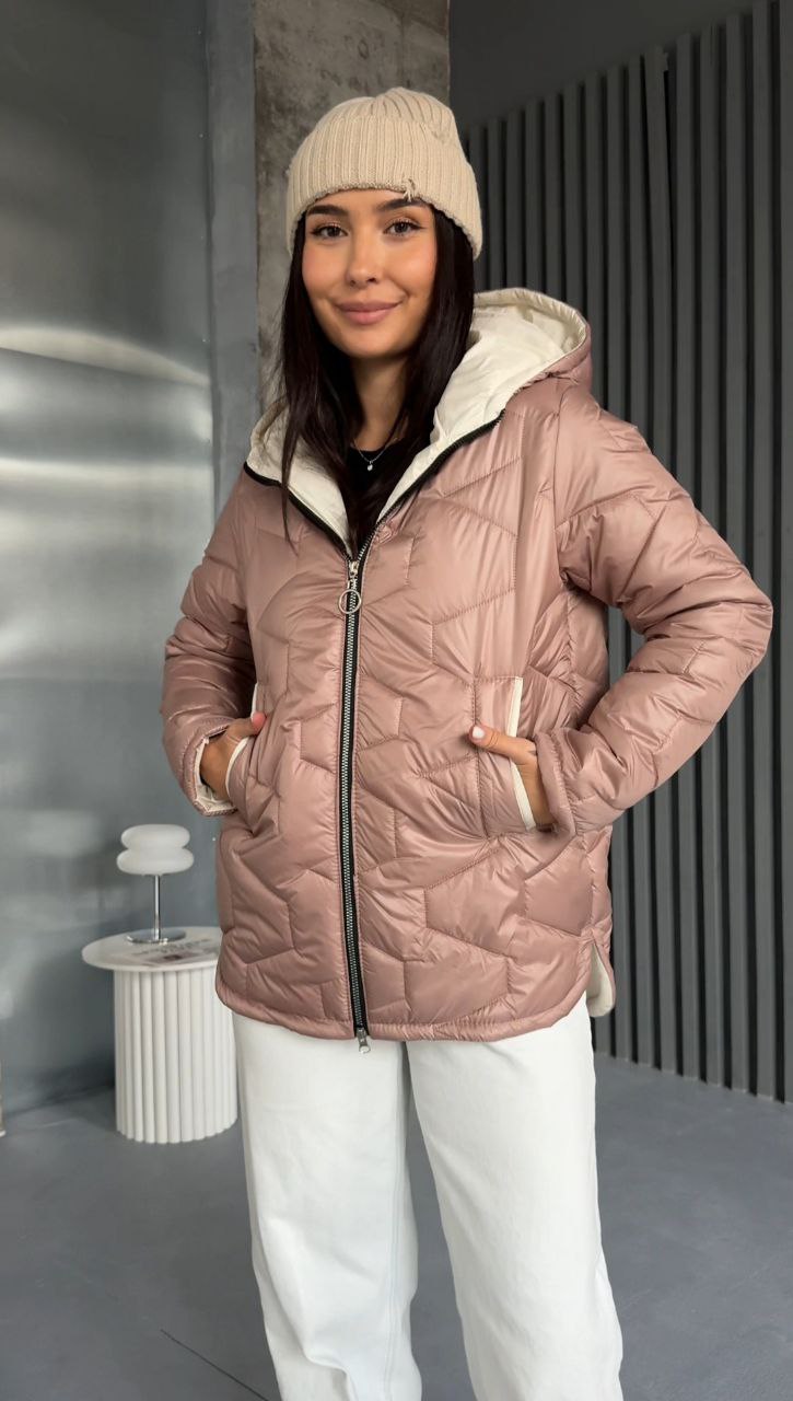 Person wearing a pink quilted jacket with a hood in an indoor setting