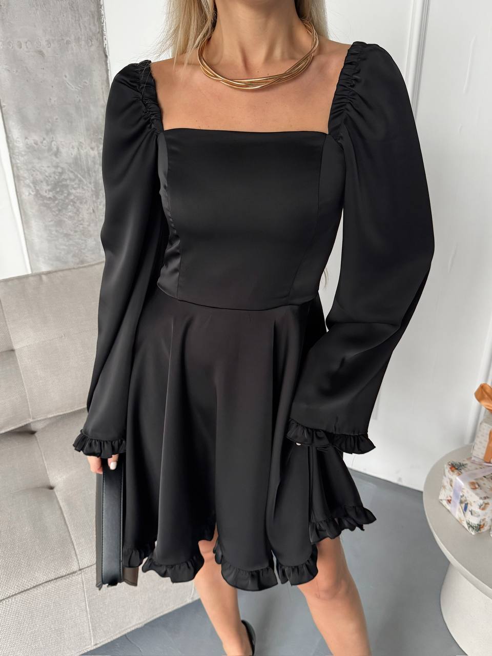 Woman wearing a black dress with long sleeves in an indoor setting