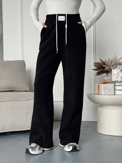 Person wearing black wide-leg pants with a white top in a room setting.