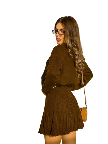 Woman wearing a brown outfit with a matching sweater and skirt, carrying a brown handbag on a white background.