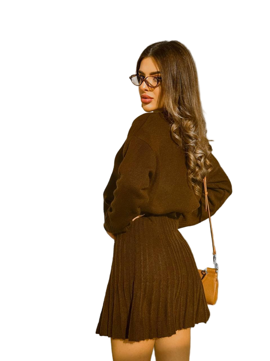 Woman wearing a brown outfit with a matching sweater and skirt, carrying a brown handbag on a white background.