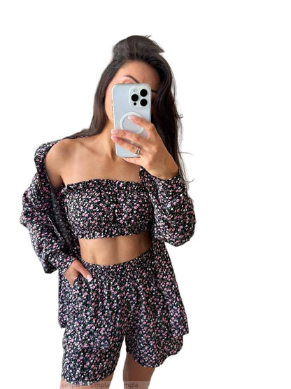 Woman taking a mirror selfie wearing a floral outfit on a white background