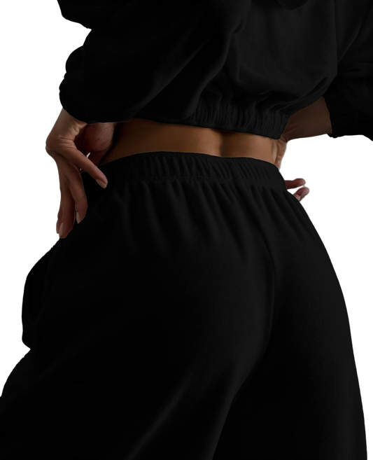 Person wearing black pants and a cropped top against a white background