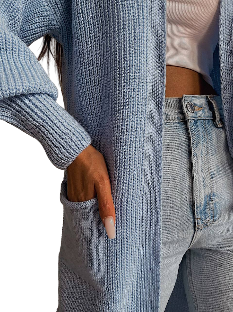 Person wearing a blue ribbed sweater and jeans with a blurred background