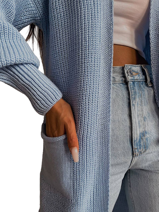 Person wearing a blue ribbed sweater and jeans with a blurred background