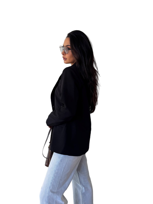 Woman wearing a black jacket and light blue jeans on a white background
