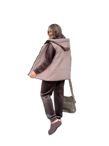 Woman wearing a beige hooded jacket and brown pants on a white background