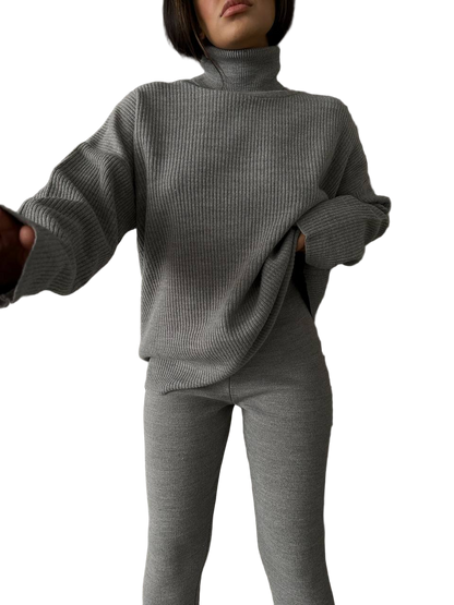 Person wearing a gray ribbed sweater and pants on a white background