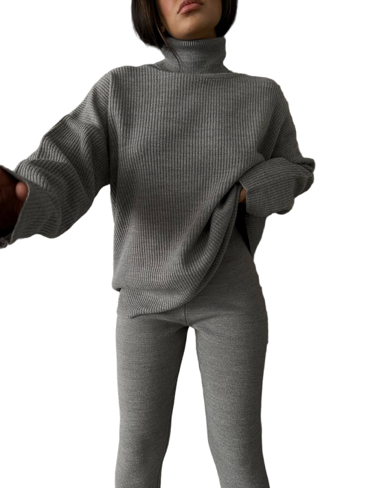 Person wearing a gray ribbed sweater and pants on a white background
