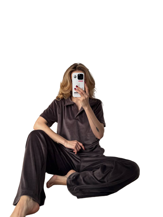 Person wearing a brown outfit sitting on the floor with a phone.