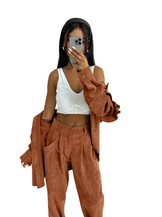 Person wearing a white top and brown corduroy pants with a brown jacket on a white background
